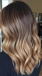 Técnica de balayagem aplicada em cabelos castanhos criando reflexos loiros suaves e efeito natural beijado pelo sol